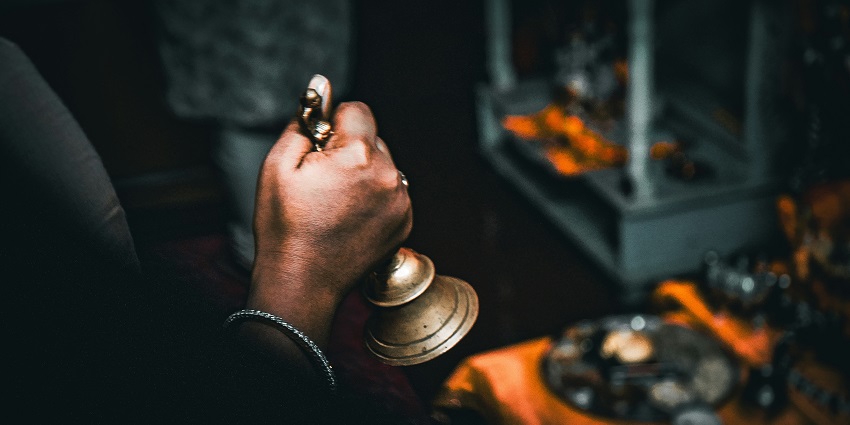 A picture of a devotee praying and ringing the holy bell at a temple in Mumbai