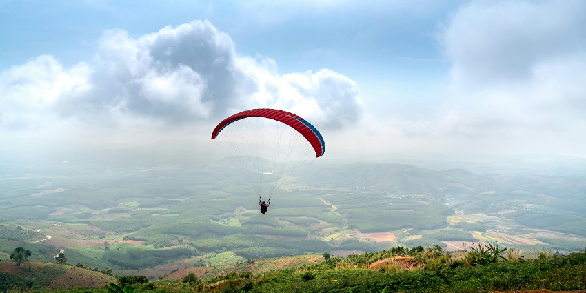 Image of a person paragliding over hills during day time - Ooty paragliding requires safety precautions