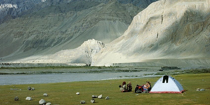 A picture of a campsite in Ladakh with a tent and tall mountains in the background