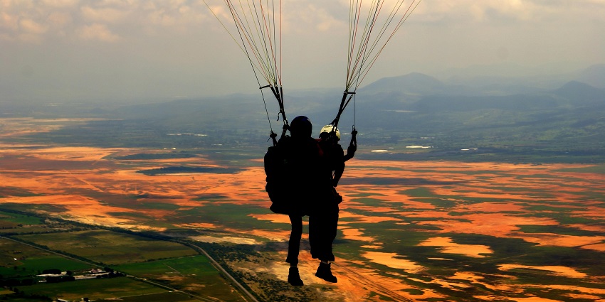 Silhouette of a person paragliding against the vibrant landscape