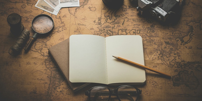 An image of travel things - a camera, a compass, a magnifying lens and more.