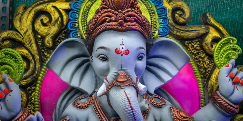 Statue of Lord Ganesha with a colorful background, famous place near Lenyadri Caves.