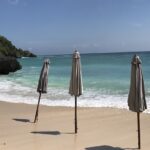 A view of a pristine Padang Padang Beach and three beach umbrellas, which are closed