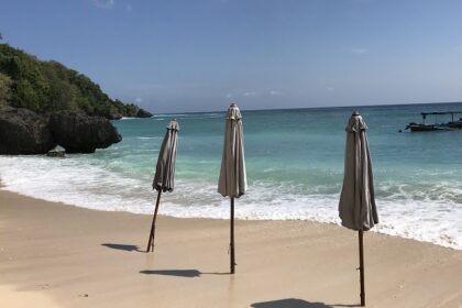 A view of a pristine Padang Padang Beach and three beach umbrellas, which are closed