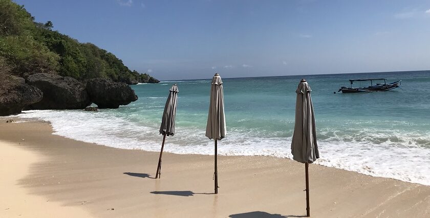 A view of a pristine Padang Padang Beach and three beach umbrellas, which are closed