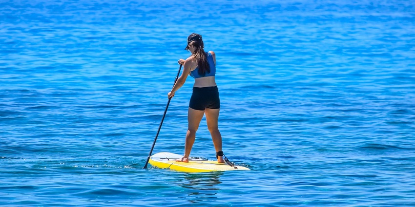 A picture of a girl paddle boarding, which is one of the best water sports in Pune.