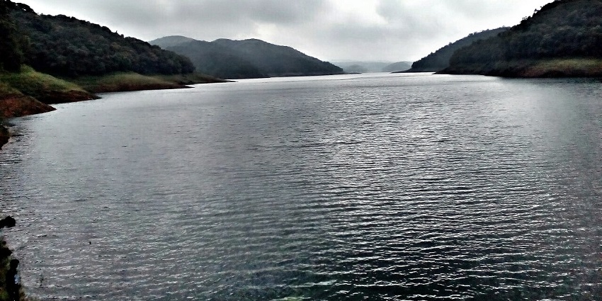 View of a serene lake in Painavu, encircled by majestic mountain ranges