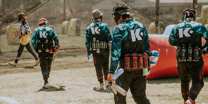 People enjoy a paintball match, using strategy and teamwork across diverse terrains.