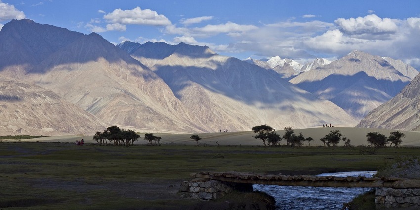A picture of a village in Ladakh with scenic vistas of greenery and mountains all around
