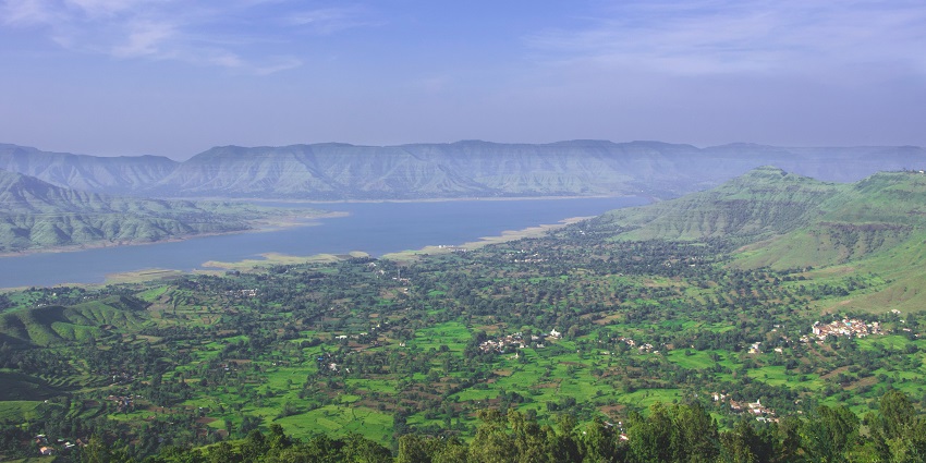 A view of a hilly landscape in Panchgani with green vegetation under a clear blue sky.