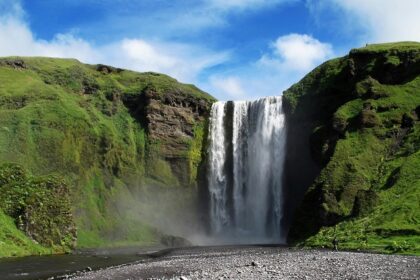 The stunning Panchgani waterfall flows gracefully in a green landscape during the daytime.