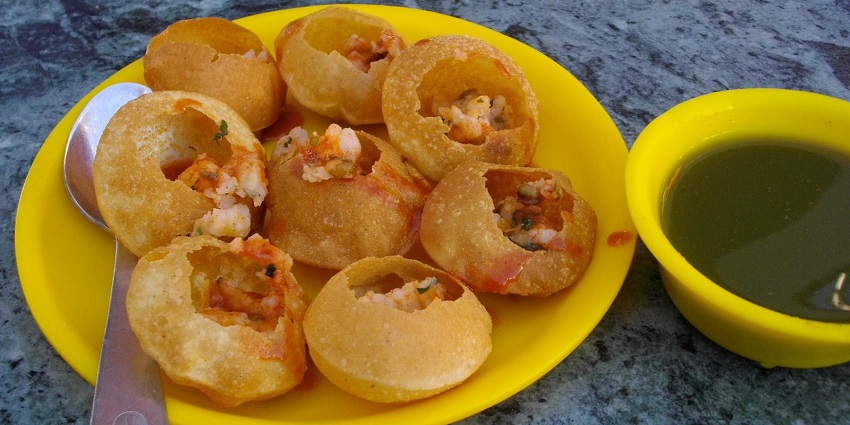 An image of some golgappas, or pani puris served on a plate with a bowl of water filling.