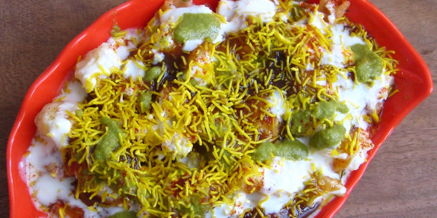 Papdi chaat served on a plate and garnished with curd and sev