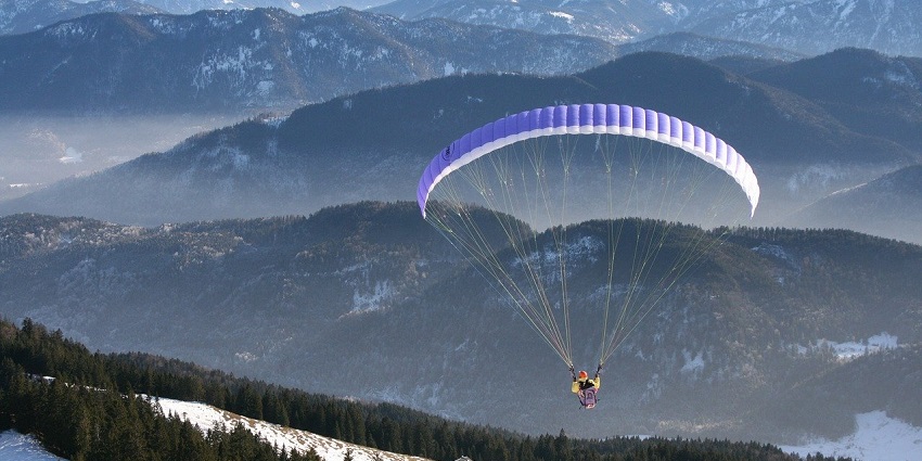 A picture of a person soaring through the skies while paragliding over the hills of Kamshet.