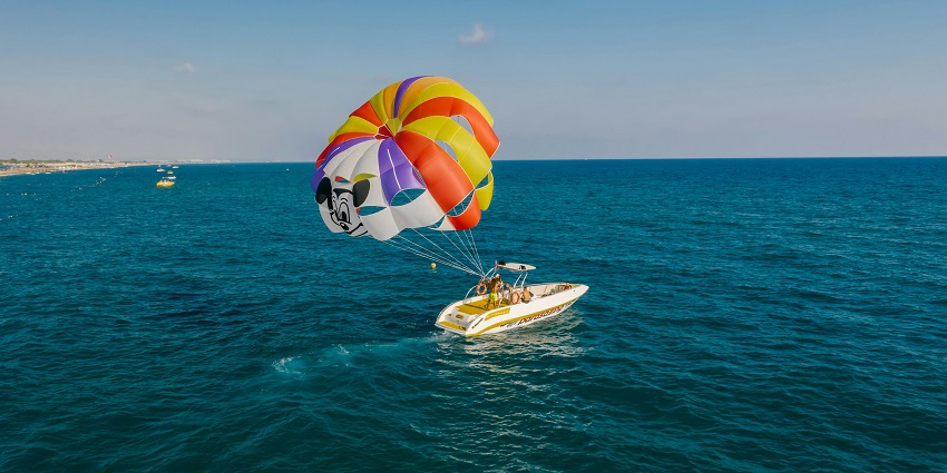 The view of tourist deploying a parachute for parasailing while riding a motorboat, one of the best water sport in Ganpatipule.