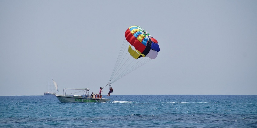 A picture of a parasailer flying high over Mulshi Lake, with a view of the lush green hills.
