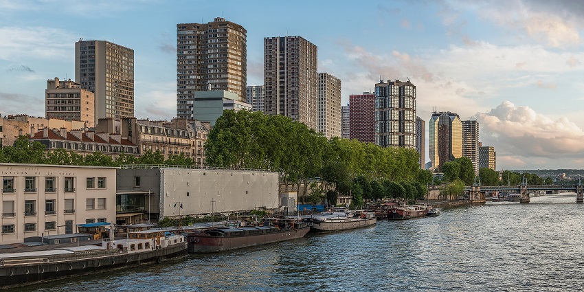 A picture of a coastline in Paris with serene blue waters and highrise buildings
