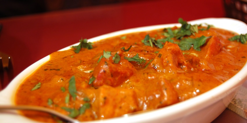 A plate of Butter Chicken, a non-veg delicacy served in a tray garnished with cilantro