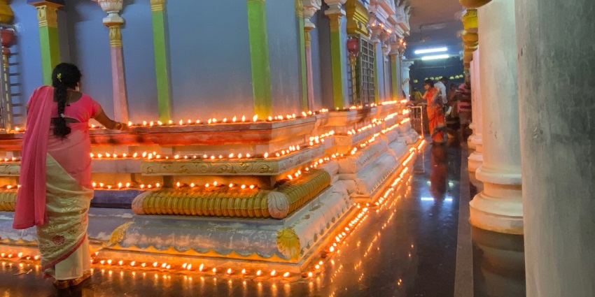 A lady putting diyas around the temple for some special puja