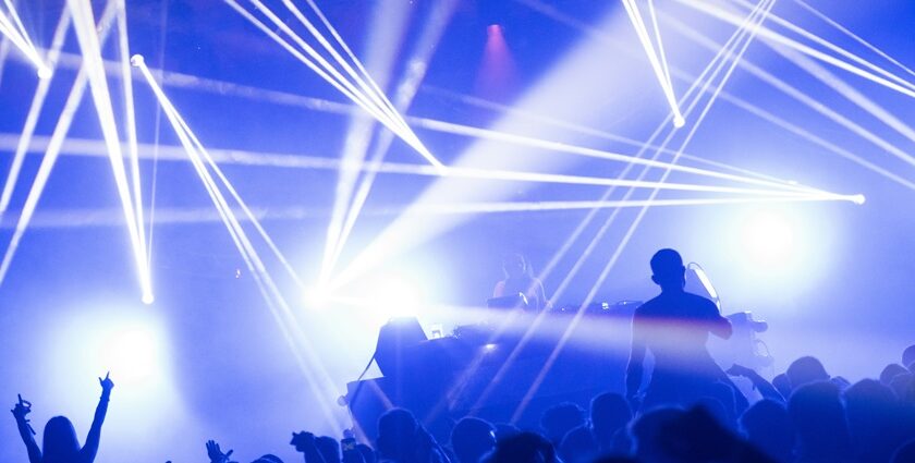 An inside view of a club decked with dazzling neon lights and people dancing.