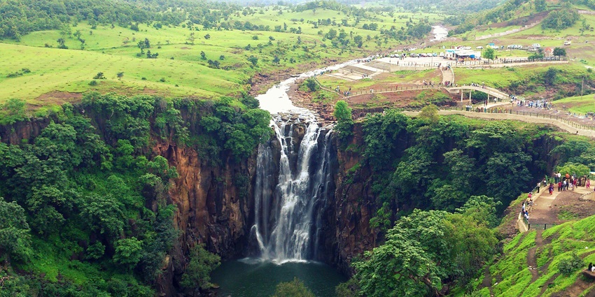 A majestic waterfall cascading from 300 feet, surrounded by hills and forests.