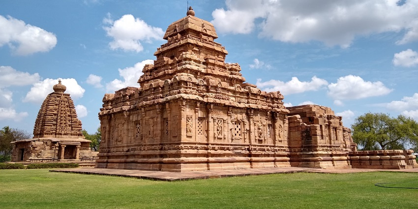 A picture of a historical temple in Pattadakal with serene views of the nearby mountains in the background