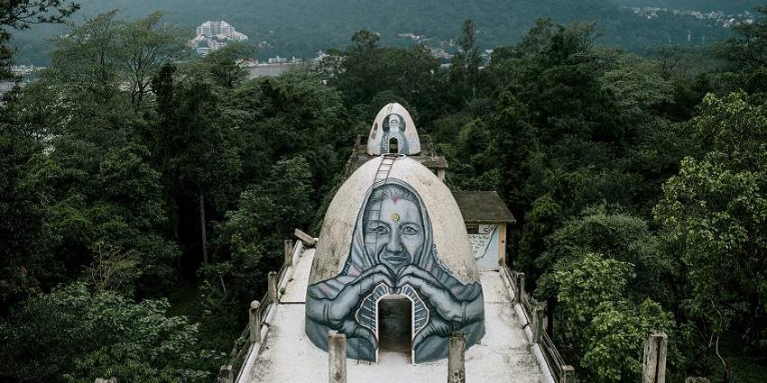 A glimpse of the Pavnar Ashram nestled at the top of a hill surrounded by lush greenery.