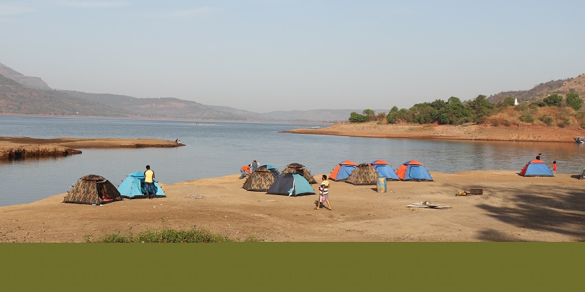 A lakeside campsite with tents and people enjoying nature near Pawna Lake