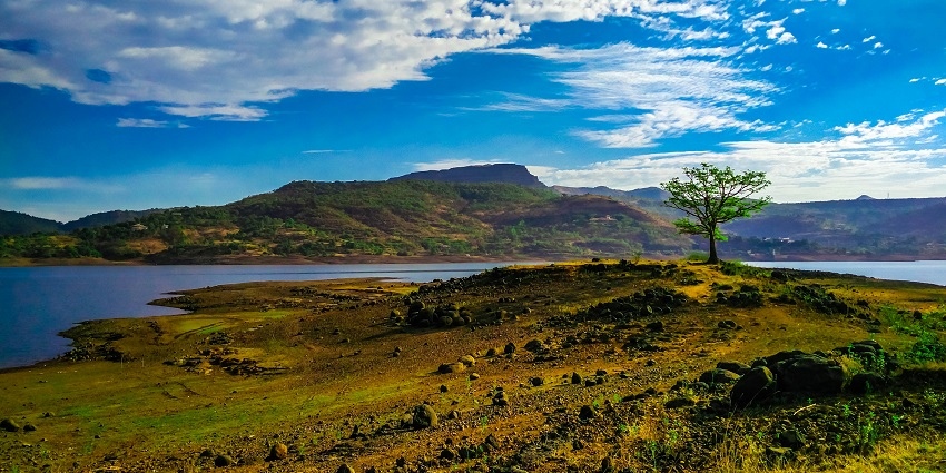 Campsite near Pawna Lake with tents set up along the shore, surrounded by hills