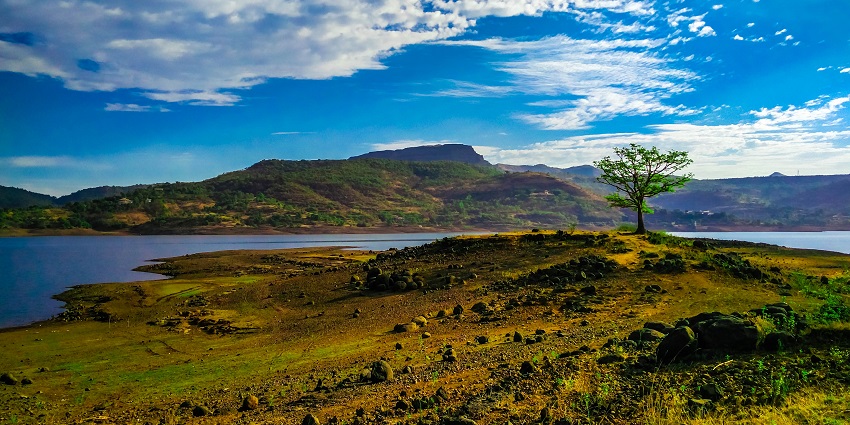 Scenic view of Pawna Lake in summer, surrounded by lush hills and clear skies.