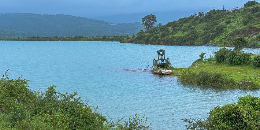 A serene view of the Pawna Lake featuring shimmering blue waters and lush greenery.