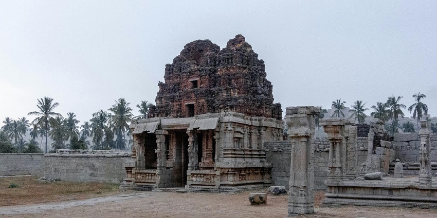 An architectural temple ruins in Madurai, with weathered stone pillars and carvings.