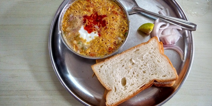 The famous Phadtare Misal served with two slices of bread, sliced onions and lime wedge