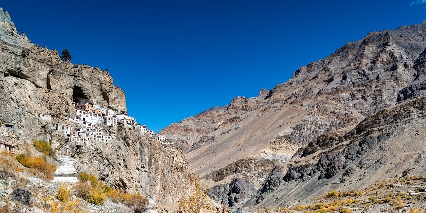 A serene view of pristine white monasteries, rustic terrains, and majestic mountains.