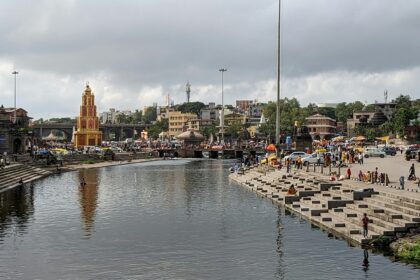 A glimpse of a ghat in Maharashtra bustling with people and featuring azure waters.