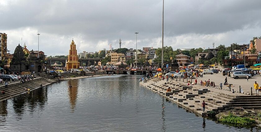 A glimpse of a ghat in Maharashtra bustling with people and featuring azure waters.