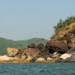 Scenic view of water and large rocks at Om Beach, a tourist attraction in Udupi.