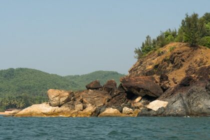 Scenic view of water and large rocks at Om Beach, a tourist attraction in Udupi.