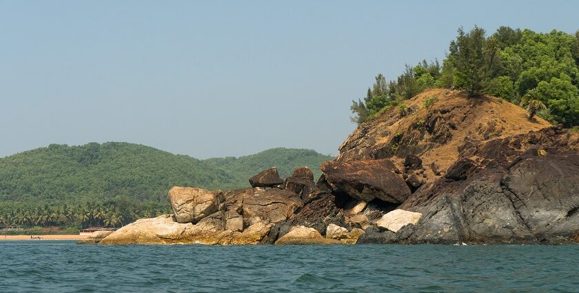 Scenic view of water and large rocks at Om Beach, a tourist attraction in Udupi.