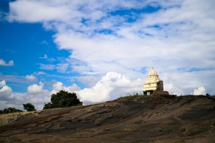 A glimpse of a temple nestled on a hill and surrounded by misty clouds in Karnataka.