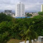 A scenic view of Hadapsar, featuring urban development, lush greenery, and a clear blue sky.