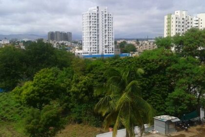 A scenic view of Hadapsar, featuring urban development, lush greenery, and a clear blue sky.