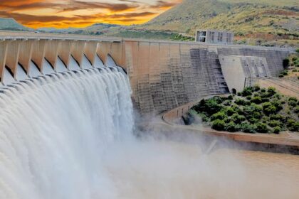 A view of a dam surrounded by lush green vegetation against a quaint backdrop.