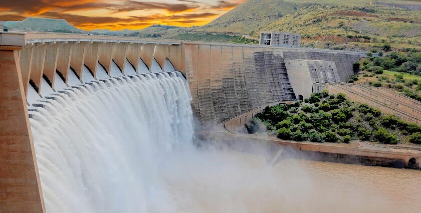 A view of a dam surrounded by lush green vegetation against a quaint backdrop.