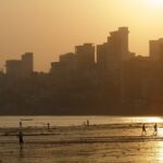 A panoramic view of the skyline of Mumbai just at sunset, with the coastline in the view.