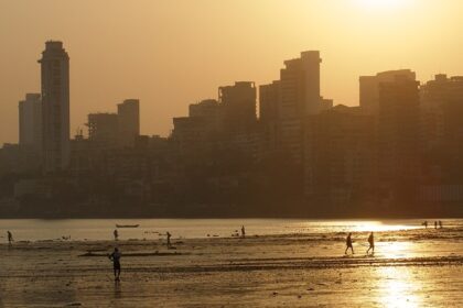 A panoramic view of the skyline of Mumbai just at sunset, with the coastline in the view.