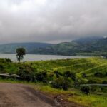 An image of Pawna Lake surrounded by lush greenery and mountains.