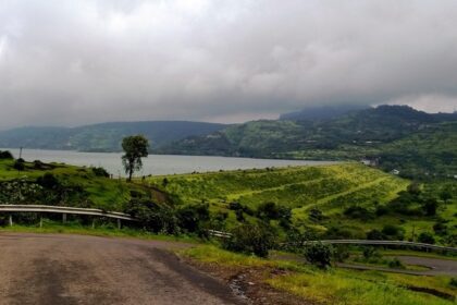 An image of Pawna Lake surrounded by lush greenery and mountains.