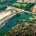 A breathtaking aerial view of a lush green valley with a stream of water flowing through.