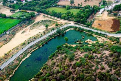 A breathtaking aerial view of a lush green valley with a stream of water flowing through.